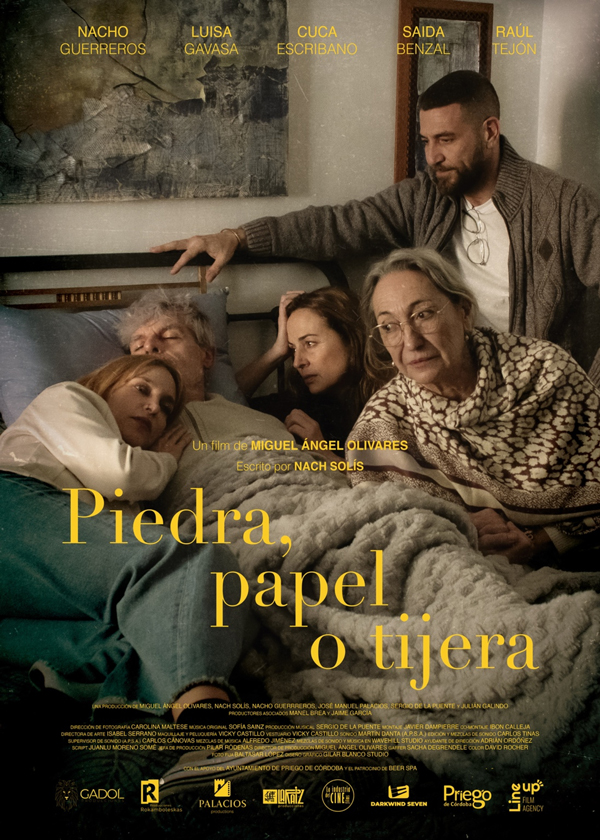 Pòster del curtmetratge 'Piedra, papel o tijera'. Mostra tres dones i dos homes a sobre d'un llit, vestits amb roba informal. Un home gran i una dona jove es veuen estirats al llit, un home amb barba i dues dones grans se'ls miren. El títol, 'Piedra, papel o tijera', està escrit en lletres grans a la part inferior. Els noms dels actors principals, com ara Nacho Guerreros i Luisa Gavasa, es troben a la part superior.